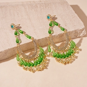 Detailed macro view of vintage gold earrings with emerald green teardrop crystals
