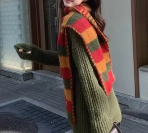Close-up of vibrant red, yellow, and green striped knit scarf paired with a green sweater