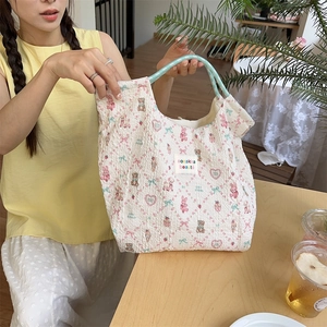 Detailed shot of quilted tote bag featuring cute cartoon patterns and mint green handles
