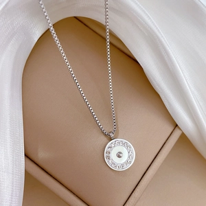 Close-up of silver titanium steel circular necklace with pavé diamonds on beige fabric