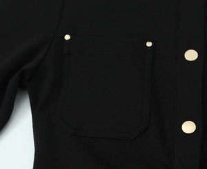Détail de la poche de robe en crêpe noir avec bouton métallique doré et texture