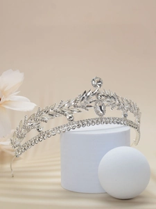 Detail of silver bridal crown with crystals on a pedestal with floral background
