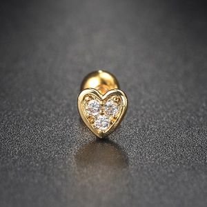 Macro detail of heart-shaped gold cartilage earring with three sparkling zircon stones