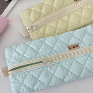 Close-up of quilted pencil cases in mint green and yellow with zipper and side handles