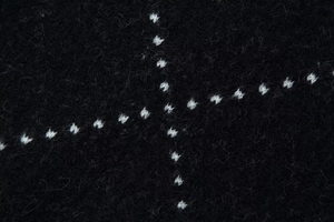 Macro view of high-density black knit fabric with white cross-stitch pattern details
