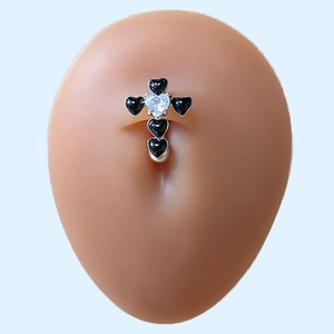 Detail of cross-shaped navel ring with black heart gems on a silicone belly model