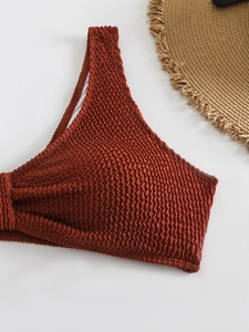 Close-up of rust red seersucker bikini top with textured fabric and beach straw hat