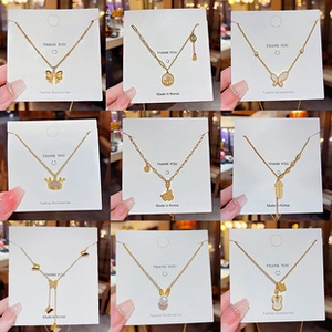 Collection of gold titanium necklaces with butterfly, crown, and pearl pendant details