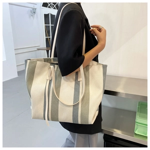 Side view of a large canvas tote bag with vertical stripes in beige and grey-green