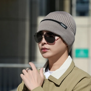 Outdoor male model wearing a thick khaki ribbed knit beanie with stylish black branding label