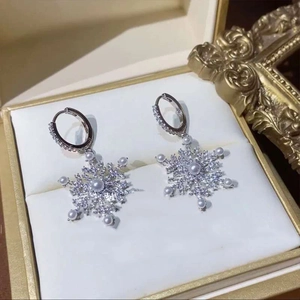 Close-up of silver snowflake tassel earrings with white pearls and sparkling zircons