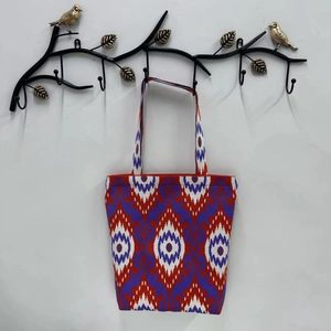 Close-up of purple and red ikat pattern canvas tote bag hanging on a decorative hook