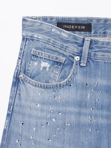 Vue détaillée du tissu en denim bleu clair avec embellissements en strass et rivets