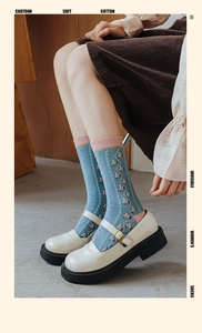 Texture détaillée de chaussettes en coton bleu clair avec fleurs roses et bord roulé
