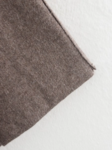 Close-up of brown wool fabric texture and detailed edge stitching on a winter coat