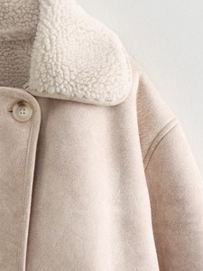 Detailed close-up of faux suede jacket with shearling collar and marbled button detail
