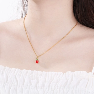 Collana a catena dorata con un piccolo ciondolo a fragola rossa indossata da una modella
