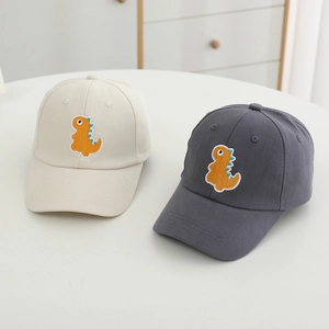 Détail de casquettes enfant beige et gris foncé avec broderie dinosaure orange