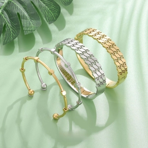 Detailed arrangement of gold and silver stainless steel bangles with natural leaf shadows