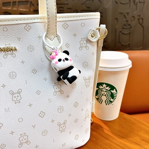 Portachiavi con panda carino appeso a una borsa tote bianca in un ambiente da bar