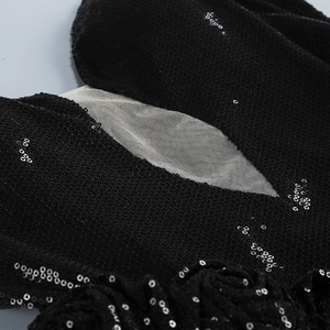 Detailed macro view of black sequins and beige mesh stitching on evening dress