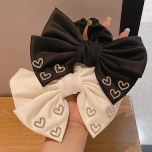 Close-up of black and white satin bow scrunchies with sparkling rhinestone heart accents