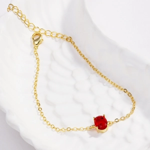 Detail of a gold-plated bracelet featuring an oval red zircon set in a four-prong mount