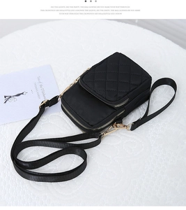 Detail view of black quilted nylon phone bag with three golden metal zippers and strap