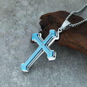 Macro shot of silver and blue double-layer cross pendant with engraved scripture