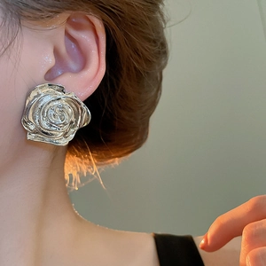 Macro primo piano di un orecchino a bottone a forma di rosa d'argento con petali metallici