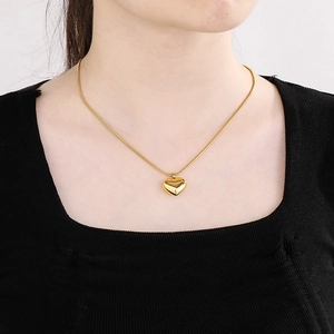 Gros plan d'un pendentif cœur doré sur une chaîne serpent porté par un mannequin de mode