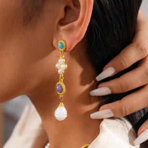 Detailed shot of vintage gold earrings with turquoise, purple stones, and baroque pearls