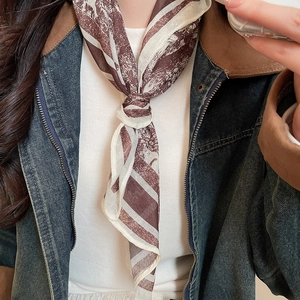 Detail of vintage printed silk scarf with brown landscape patterns tied on a woman's neck