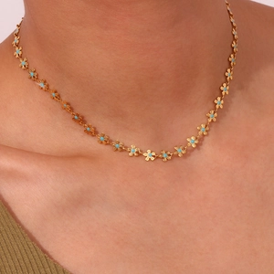 Golden flower necklace with blue enamel centers worn by a model for a stylish look