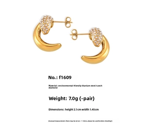 Macro detail of gold-plated crescent earrings with inlaid crystals and titanium steel texture