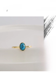 Detailed close-up of a vintage gold ring featuring a polished oval turquoise stone on white ceramic