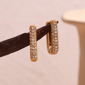 Detail of 18K gold plated rectangular earrings with micro-set zircon on wood stand