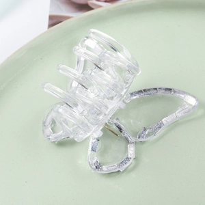 Vue rapprochée d'une pince à cheveux papillon transparente sur une assiette en céramique