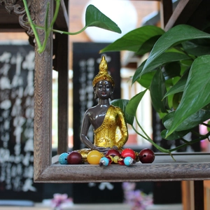 Golden Thai Buddha statue with colorful prayer beads in a Zen home decor setting