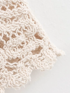 Gros plan sur tissu au crochet crème avec motifs ajourés et détails de bords ondulés