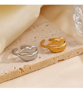 Detail showing gold and silver lip-shaped rings with brushed metal texture and open band