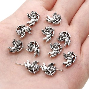 Close-up of silver cupid angel wing charms on palm for DIY jewelry making material