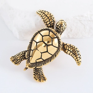 Macro detail of golden turtle pendant with polished shell textures on white rock