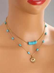 Detail of 14K gold plated layered necklace featuring turquoise beads and sunburst heart pendant