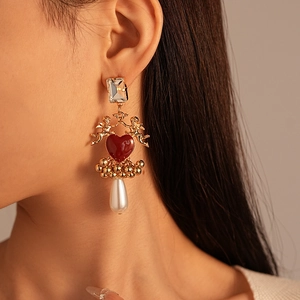 Gros plan de boucles d'oreilles cœur vintage avec relief ange et perles sur modèle