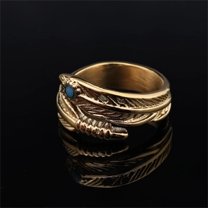Golden stainless steel feather ring with round turquoise stone on black mirror background