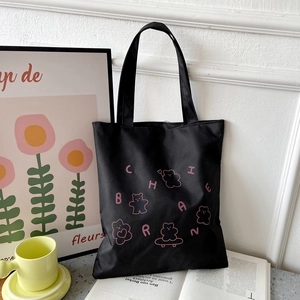 Detail of black canvas tote with pink letter print and cute bear patterns on a desk