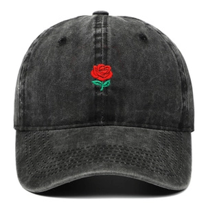 Close-up of red rose embroidery on a washed dark gray cotton denim baseball cap