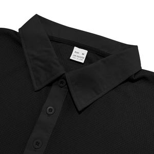 Detail of black waffle knit texture on men's polo shirt with collar and button focus