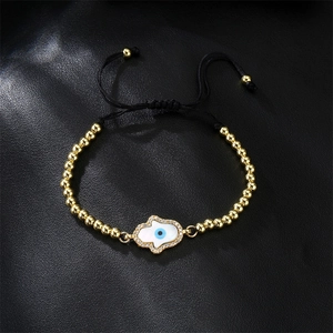 Macro detail of Hamsa Hand charm with shell inlay and zircon on woven beaded bracelet